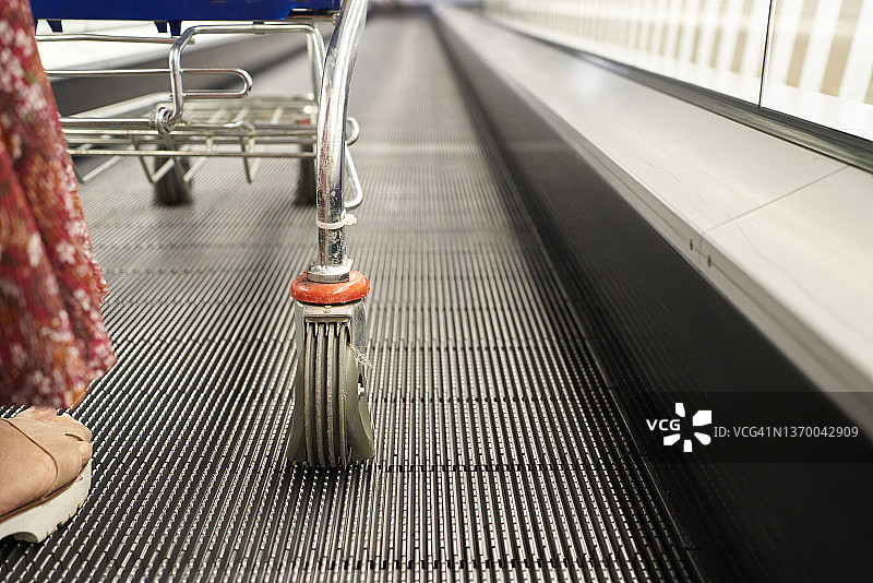 超市传送带上推购物车的女人脚部特写图片素材