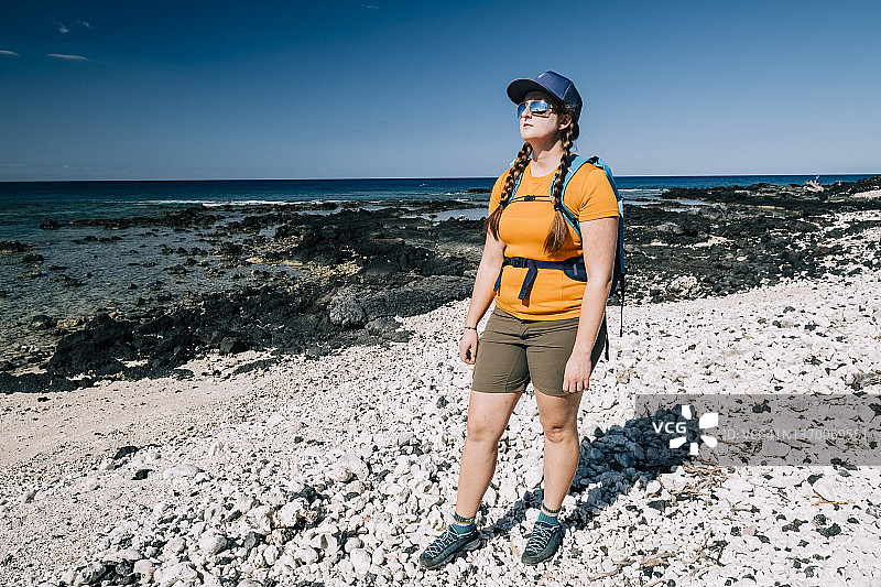 一位年轻女人站在夏威夷大岛的岩石海滩上图片素材
