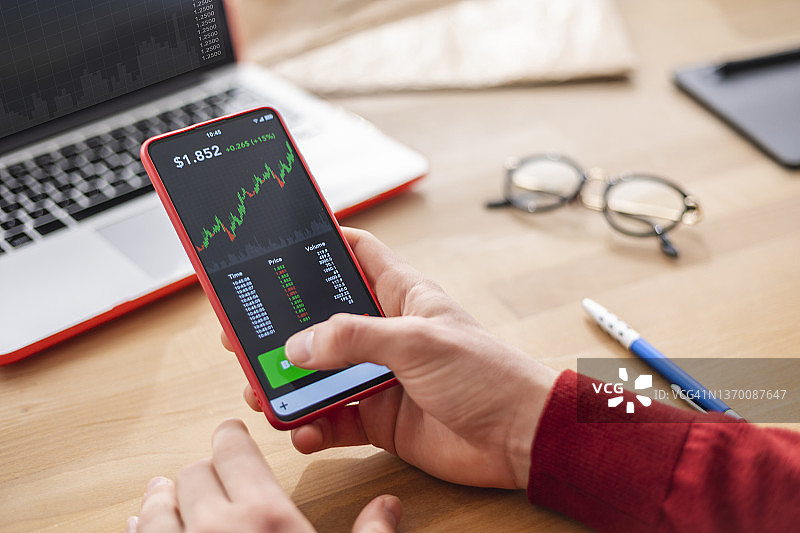 男人使用手机App查看股市投资和交易图片素材