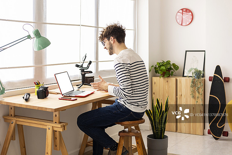 坐在桌旁使用笔记本电脑的年轻人图片素材