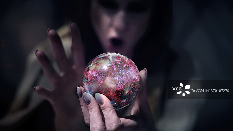 迷人的占卜女郎手持玻璃球，里面有神奇的发光粉尘图片素材