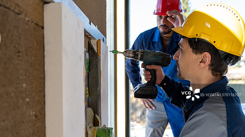 使用充电钻在墙上安装设备图片素材