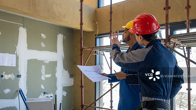 两名建筑工人阅读蓝图并讨论图片素材