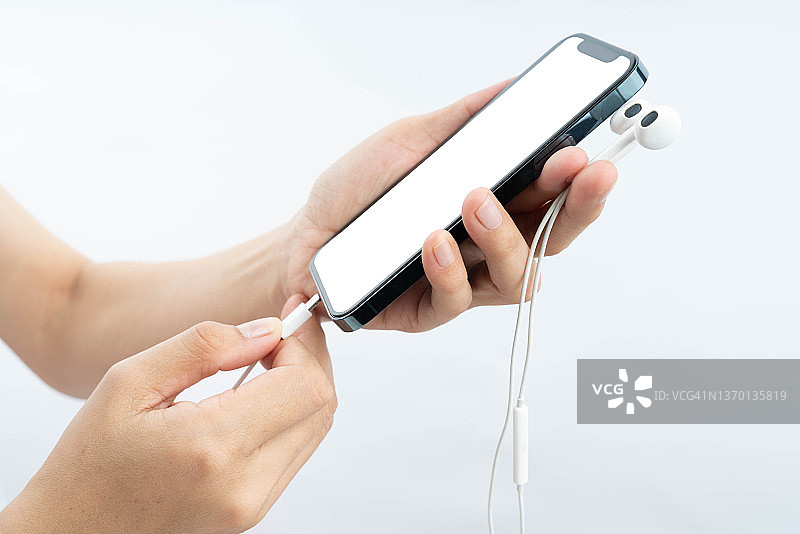 年轻女子将耳机连接到智能手机的特写镜头图片素材