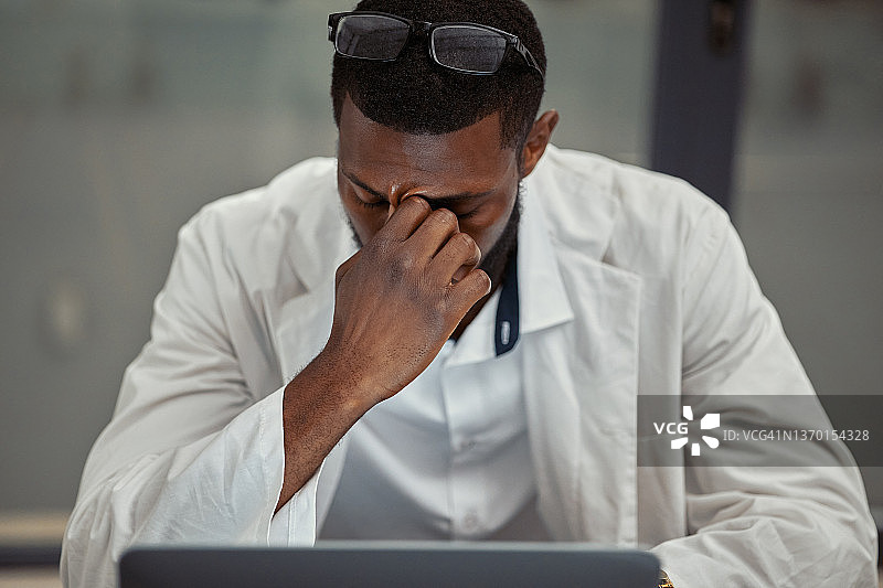 年轻科学家在实验室用笔记本电脑工作时感到压力图片素材