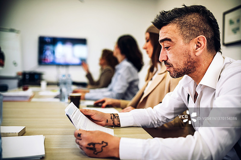 商务人士在办公桌前交流，同事在办公室开会讨论图片素材