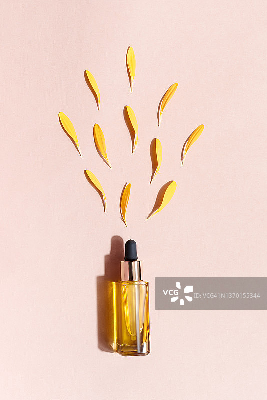 米色背景上的化妆品瓶和黄色非洲菊：自然化妆品概念图片素材