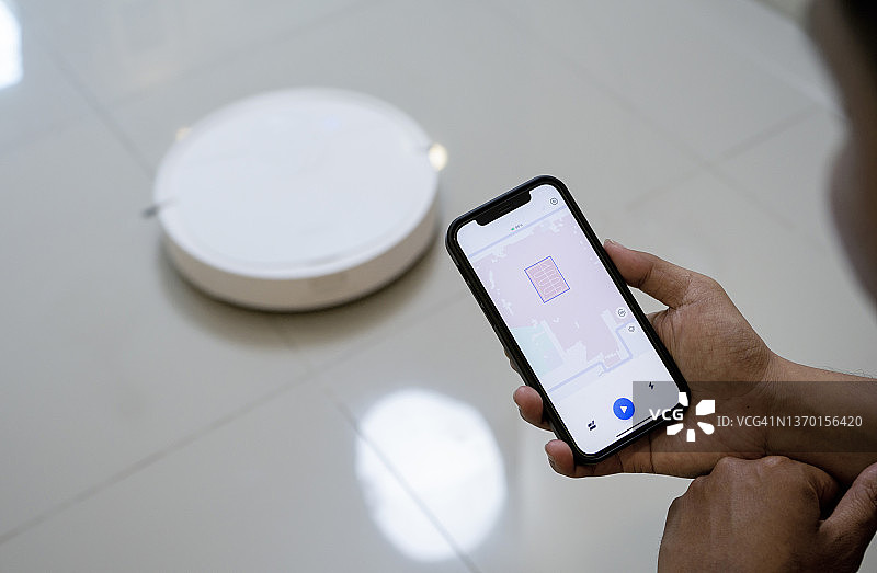 在智能手机上使用机器人吸尘器应用程序图片素材