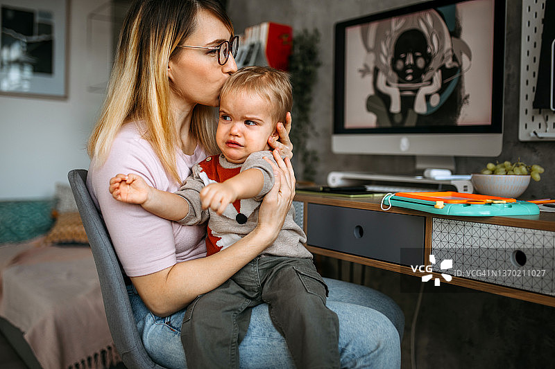 母亲抱着正在哭泣的男婴图片素材