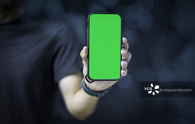 商人拿着带有绿色空白屏幕的智能手机图片素材