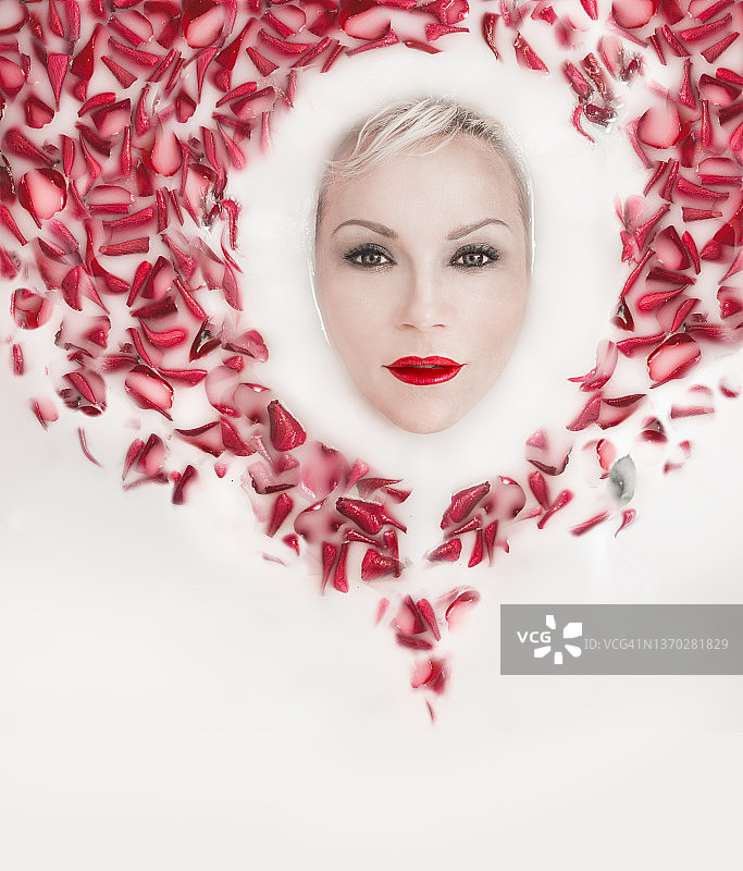 红唇美女在漂浮的玫瑰花瓣牛奶浴中图片素材