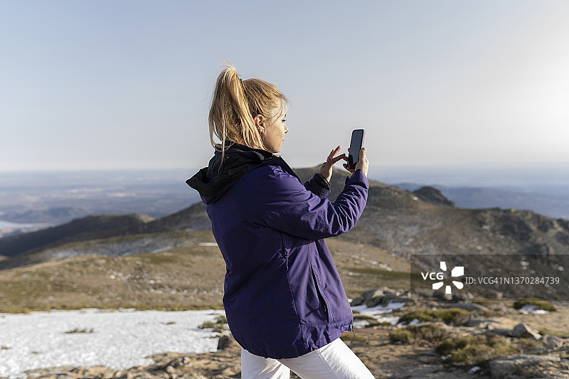 漂亮的女背包客用智能手机拍摄风景图片素材