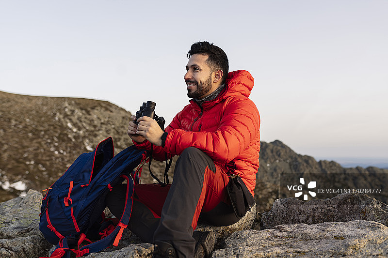 背包客在山上用双筒望远镜观察图片素材