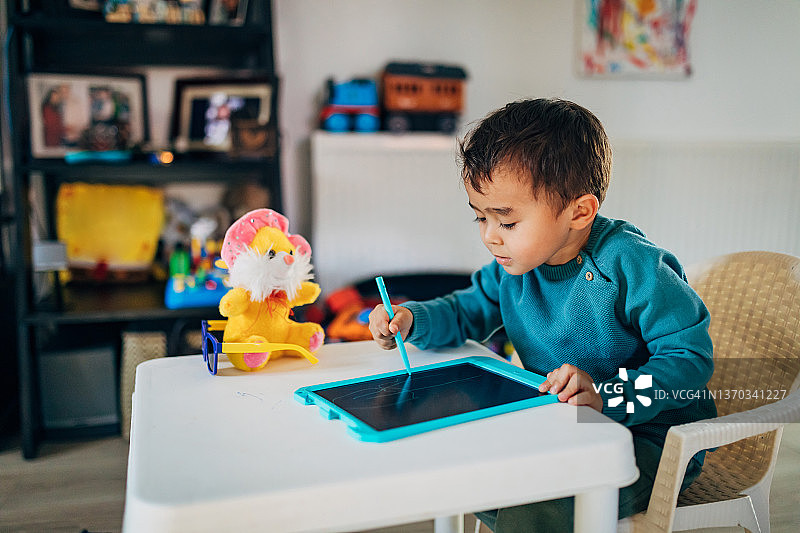可爱的混血男孩学习绘画，使用儿童可擦写画板图片素材