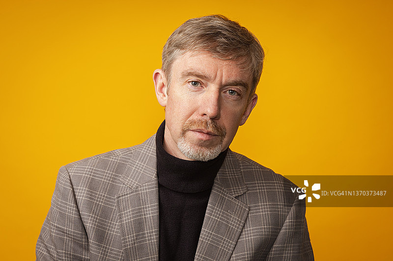 黄色背景下穿格子夹克的50岁络腮胡男士特写图片素材