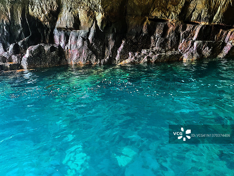 海蚀洞内的碧绿色海水与岩石海岸图片素材