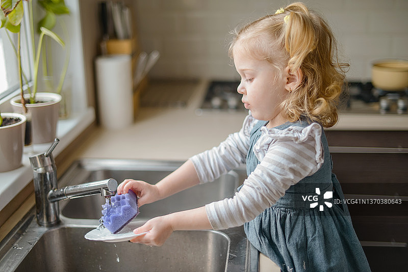 在室内洗碗的金发女婴图片素材