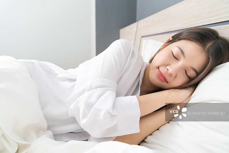 享受床上用品的年轻漂亮亚洲女子图片素材