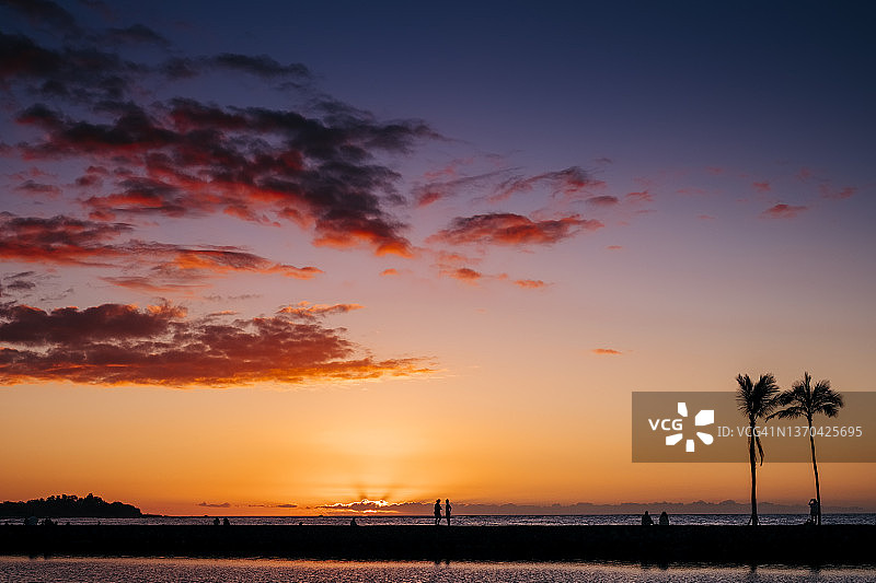 人们在夏威夷大岛标志性海滩欣赏壮丽的日落图片素材