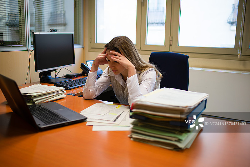 在办公室里手扶头的疲惫员工图片素材