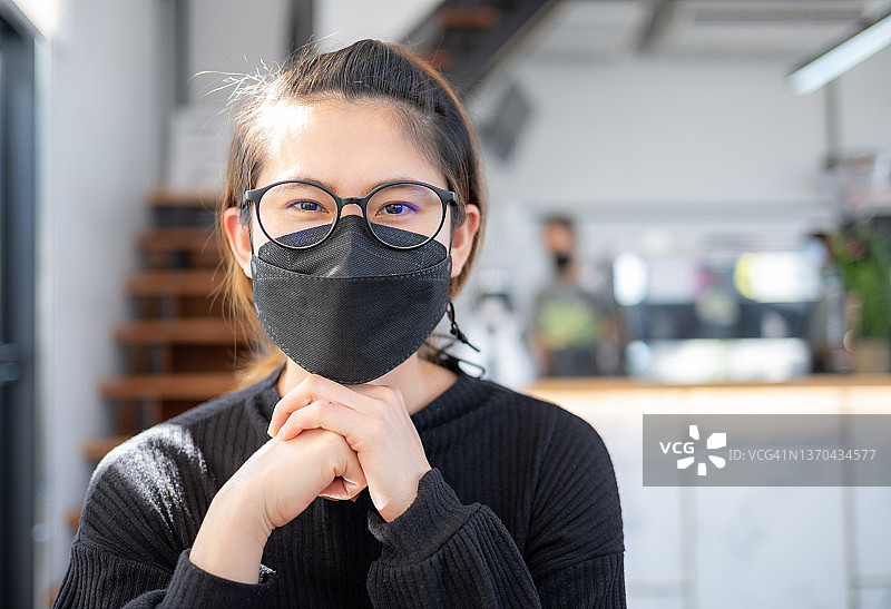 疫情后，戴着口罩微笑的快乐亚洲年轻女性的新常态生活图片素材