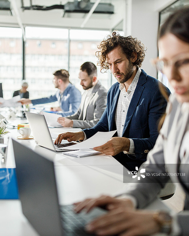 年轻商人在办公室使用电脑和处理文件图片素材