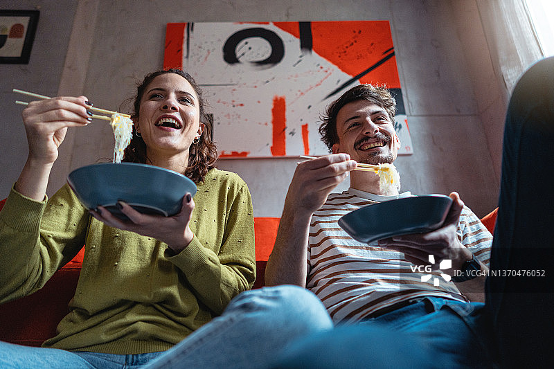 快乐而宁静的年轻情侣吃面条，看电影图片素材