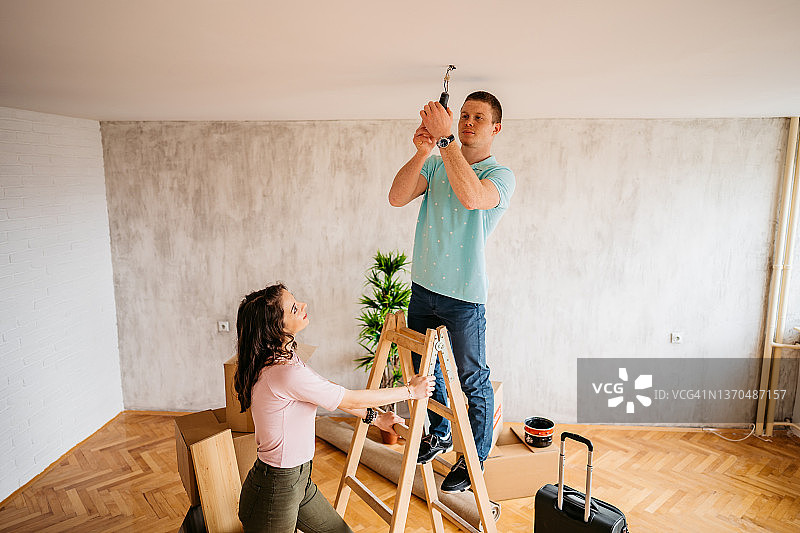 男友在新公寓里帮女友换灯泡图片素材