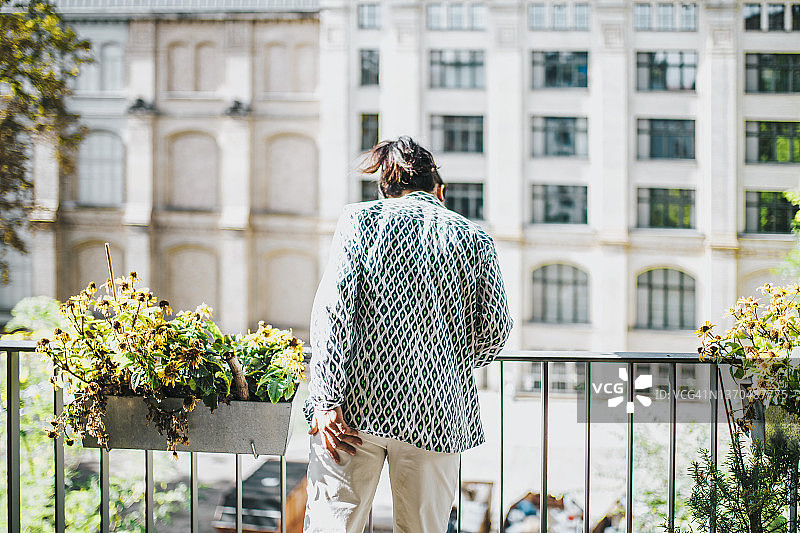 女人在阳光明媚的阳台上向下看图片素材