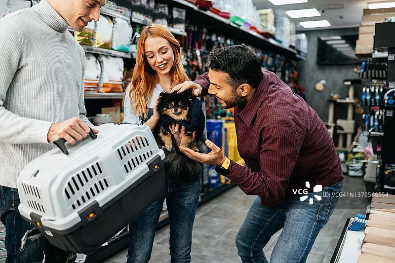 快乐情侣在宠物店为小狗购买玩具和狗粮图片素材