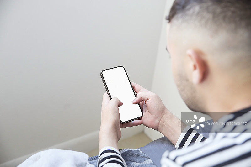 拉丁裔男子在家使用手机（肩后视角）图片素材