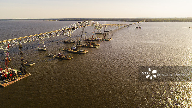弗吉尼亚州和马里兰州之间的哈里·W·奈斯纪念/托马斯“麦克”米德尔顿参议员大桥重建工程航拍，波托马克河沿岸有多个浮动式起重机船只和建筑工地图片素材