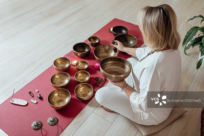 白衣金发欧洲女子演奏西藏颂钵图片素材