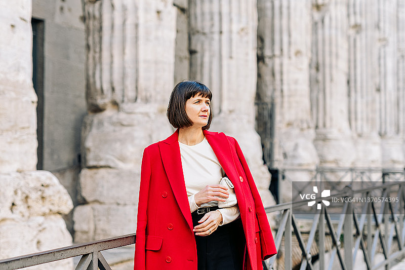 身穿红色外套的年轻漂亮女人走在意大利罗马的街道上图片素材