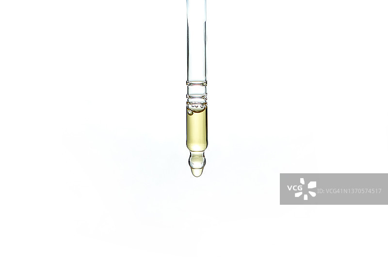 白色背景下玻璃移液器中一滴黄色油的特写。图片素材