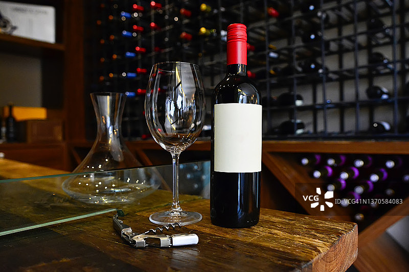 迷人餐厅地窖中乡村木桌上的红酒瓶、酒杯和开瓶器图片素材