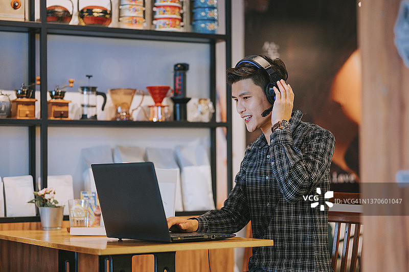 中国男人在咖啡馆用笔记本电脑进行视频通话工作图片素材