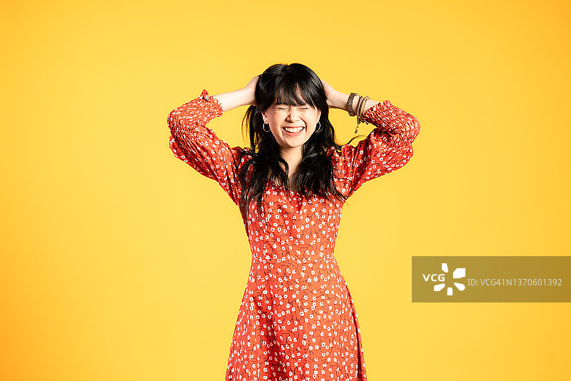 笑容满面的女子，在黄色背景下闭着眼睛图片素材