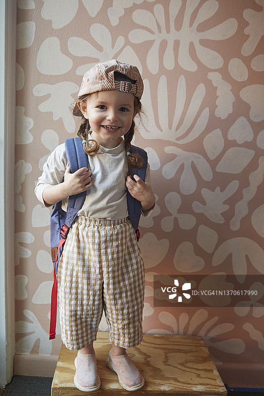 戴着背包和棒球帽、靠在涂鸦墙上的女童图片素材