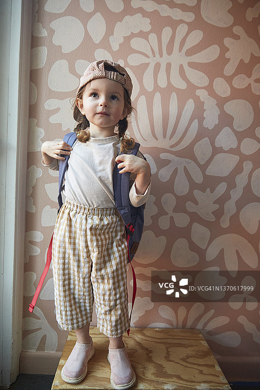 背着背包戴着棒球帽站在涂鸦墙前的快乐幼儿图片素材