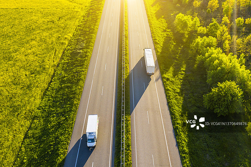 乡村绿色田野中卡车在沥青路上行驶的航拍景色图片素材