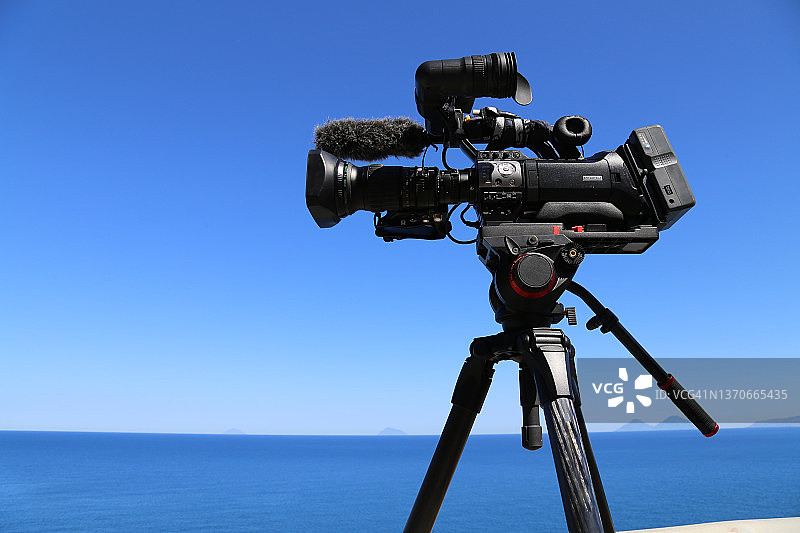 带蓝色天空背景的三脚架上的专业摄像机图片素材
