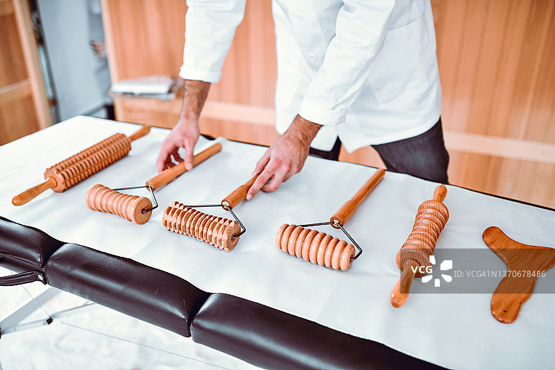 现代按摩师调整桌子上木制按摩工具的位置图片素材