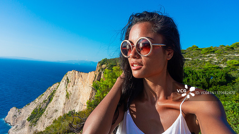 年轻漂亮的异域女子在户外自拍，背景是美丽的自然风光图片素材