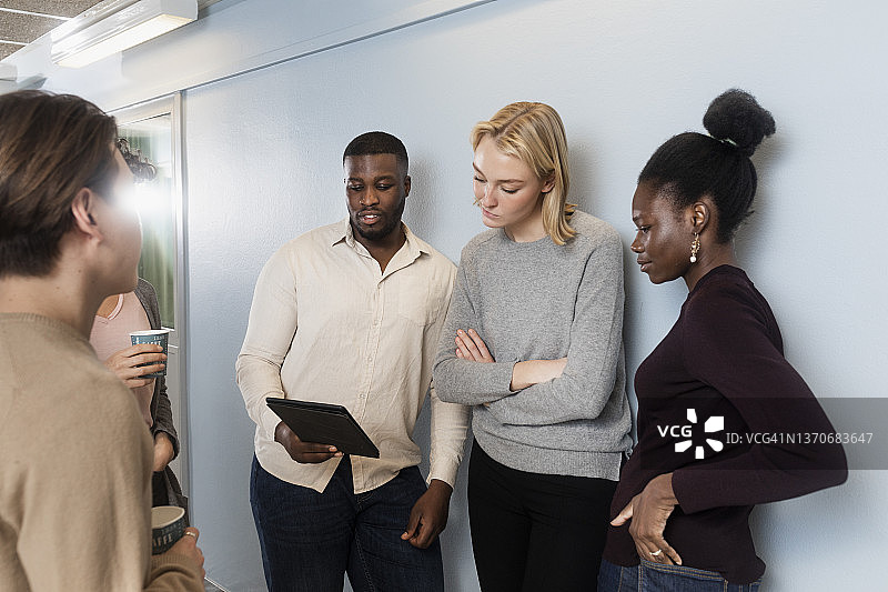 同事们在咖啡休息时间看平板电脑图片素材