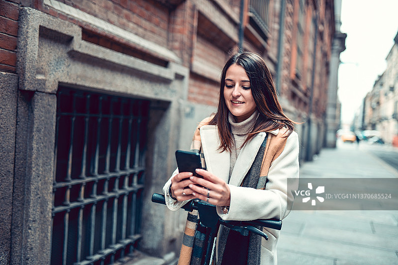 使用电动滑板车和智能手机地图在城市中寻找方向的女人图片素材
