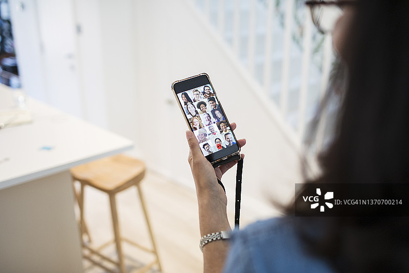 女人在手机屏幕上与同事视频聊天。图片素材