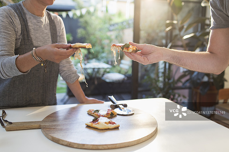 情侣在餐桌旁享用自制披萨图片素材