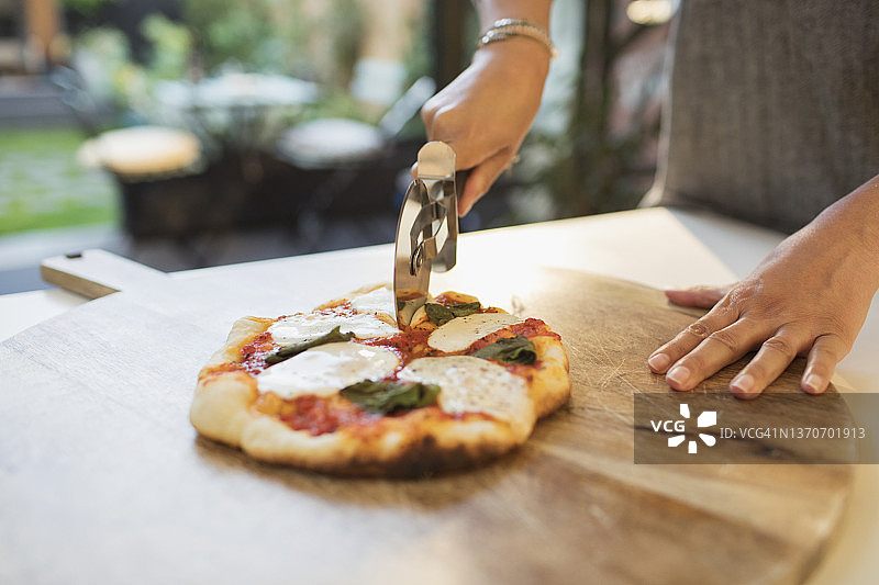 女人用切片刀切新鲜自制披萨图片素材