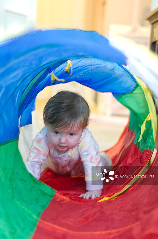 爬行通过玩具隧道的婴儿图片素材